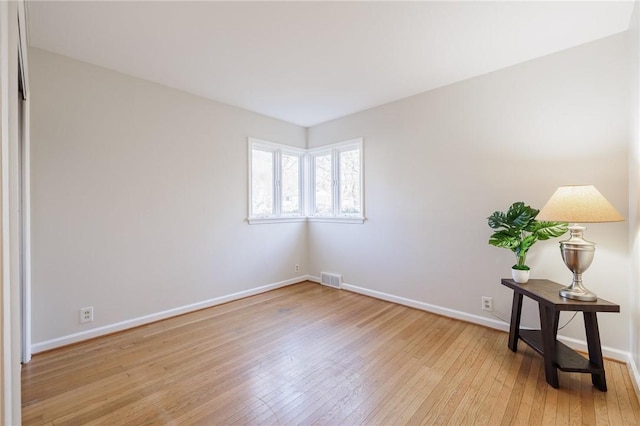 empty room featuring visible vents, light wood-style flooring, and baseboards