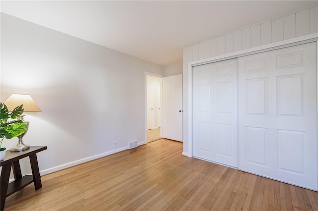 unfurnished bedroom with light wood finished floors, visible vents, a closet, and baseboards