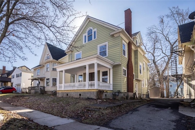 view of front facade featuring a residential view, a porch, and a chimney