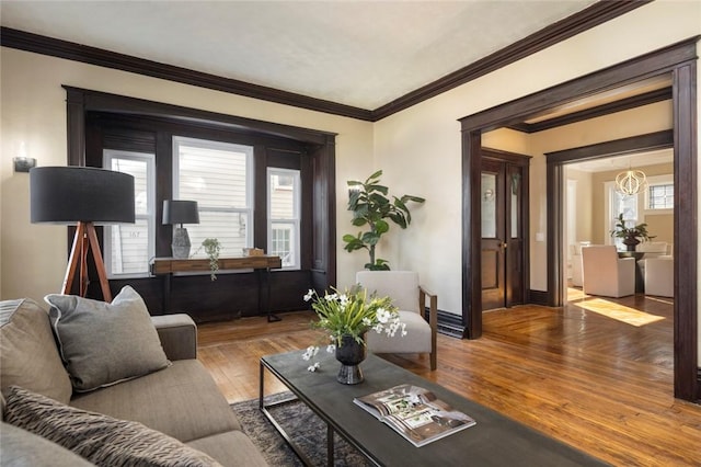 living room with a wealth of natural light, baseboards, wood finished floors, and crown molding