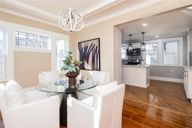 dining space with dark wood finished floors, crown molding, a notable chandelier, and a healthy amount of sunlight