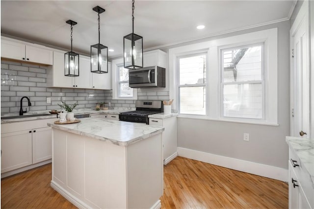 kitchen featuring light wood finished floors, a sink, white cabinets, appliances with stainless steel finishes, and backsplash