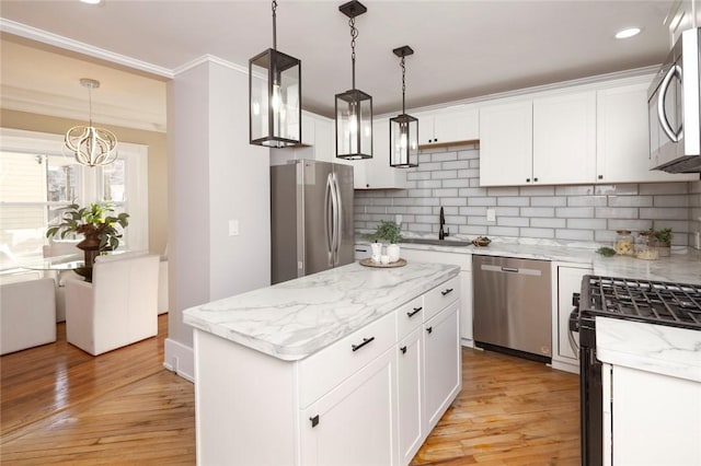 kitchen featuring a sink, stainless steel appliances, white cabinets, light wood-type flooring, and backsplash