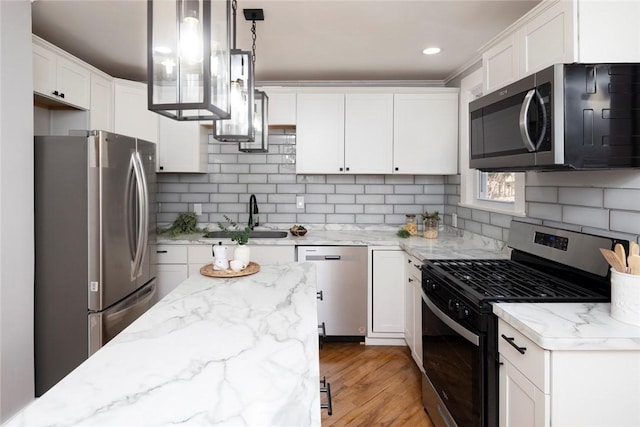 kitchen with light wood-type flooring, a sink, white cabinets, appliances with stainless steel finishes, and tasteful backsplash