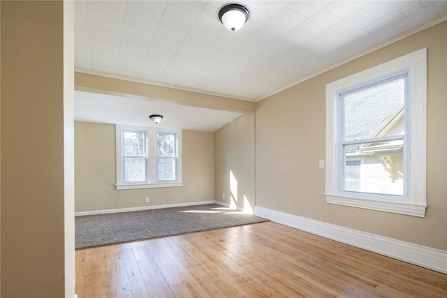 unfurnished room featuring crown molding, baseboards, and wood finished floors