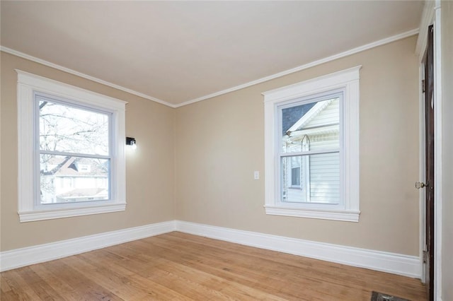 spare room featuring light wood-type flooring, baseboards, and ornamental molding