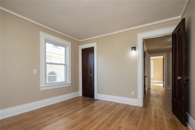 unfurnished room with light wood-style flooring, crown molding, and baseboards