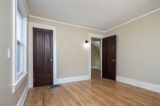 spare room featuring a wealth of natural light, visible vents, baseboards, and light wood finished floors