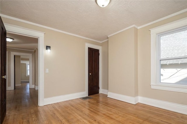 unfurnished room featuring a wealth of natural light, baseboards, light wood finished floors, and ornamental molding