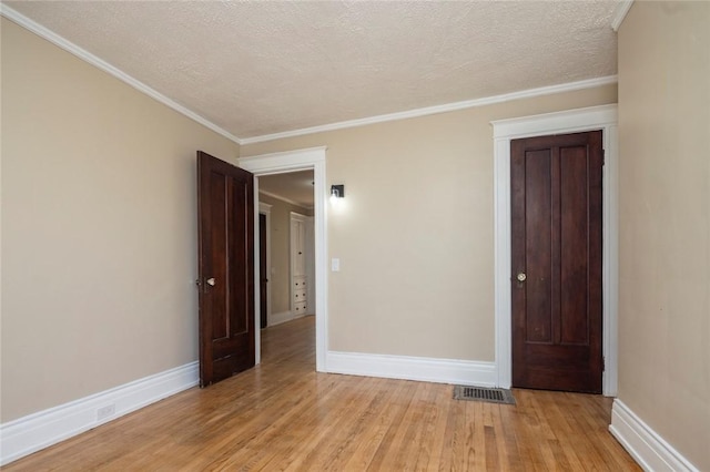 empty room featuring baseboards, visible vents, light wood finished floors, and a textured ceiling