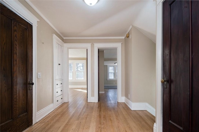 corridor with light wood-type flooring, baseboards, and ornamental molding