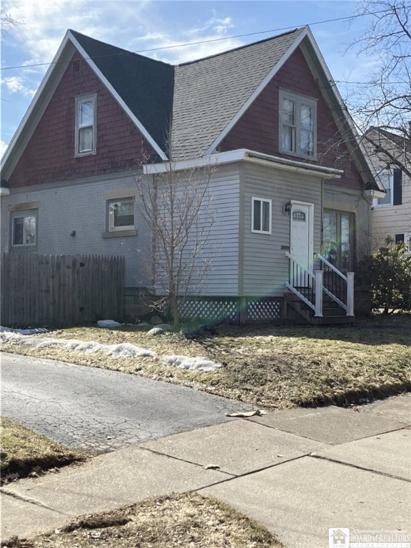 view of front of house with entry steps, fence, and a shingled roof