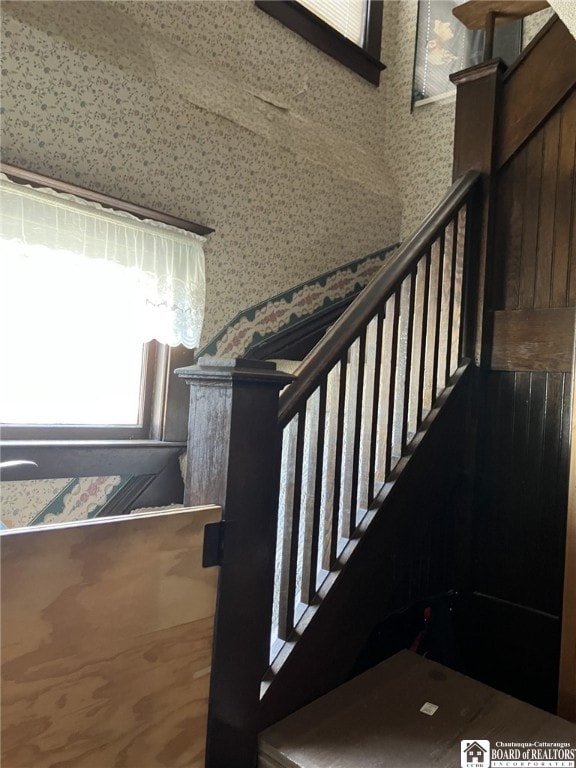 stairs featuring wallpapered walls