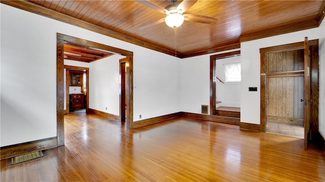 spare room with crown molding, wood finished floors, baseboards, and wooden ceiling