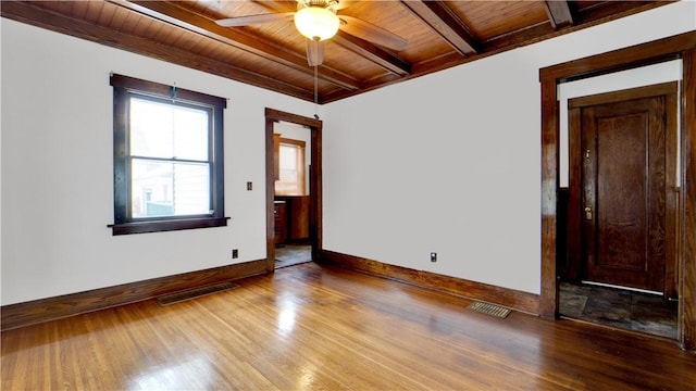 empty room with visible vents, beam ceiling, wood ceiling, and wood finished floors