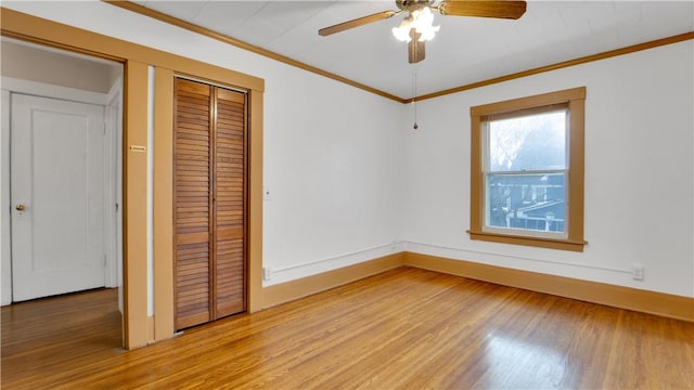 unfurnished bedroom featuring baseboards, ceiling fan, light wood-style floors, a closet, and crown molding