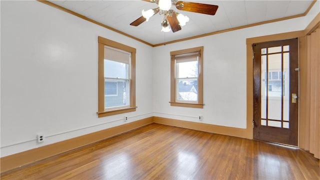 empty room with ceiling fan, baseboards, wood finished floors, and ornamental molding