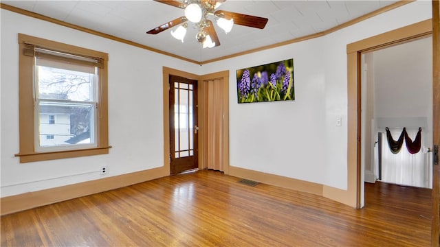 spare room with wood finished floors, baseboards, and ornamental molding