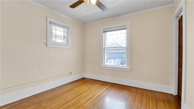 unfurnished room featuring wood finished floors, a healthy amount of sunlight, and baseboards