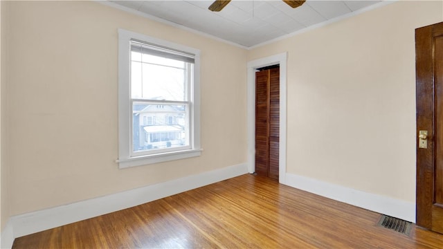 unfurnished room with wood finished floors, baseboards, visible vents, ceiling fan, and ornamental molding