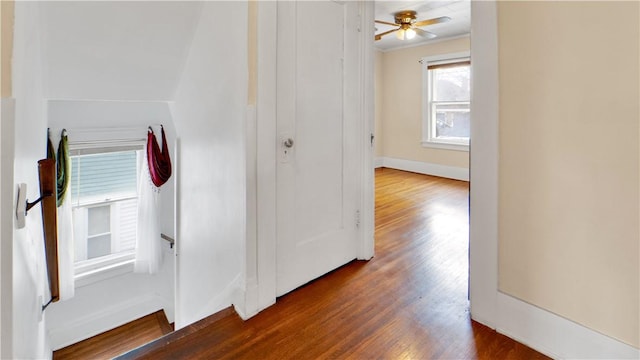 corridor featuring crown molding, baseboards, and wood finished floors