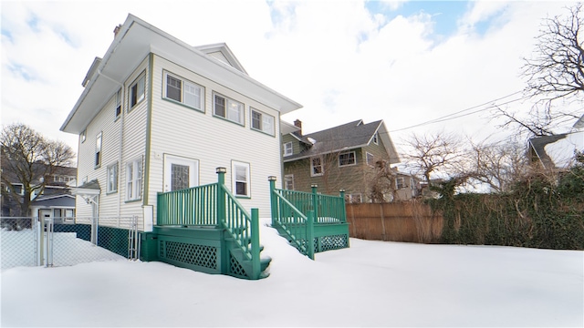 snow covered back of property with fence and a gate