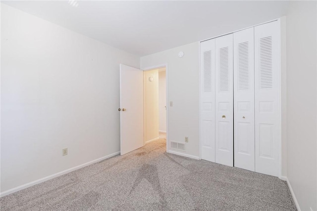 unfurnished bedroom with a closet, visible vents, carpet flooring, and baseboards