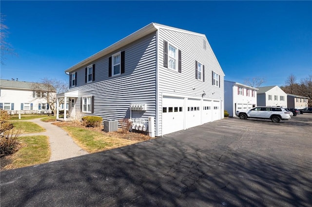 view of side of home featuring a garage, a residential view, and central AC