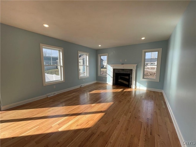 unfurnished living room with visible vents, baseboards, wood finished floors, and a fireplace