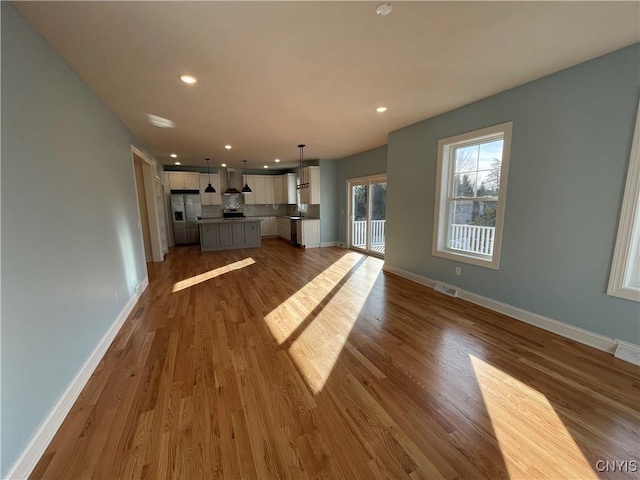 unfurnished living room with recessed lighting, wood finished floors, visible vents, and baseboards