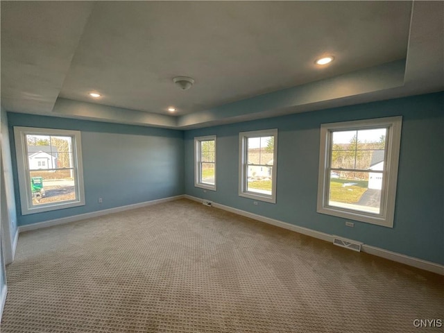 carpeted spare room featuring recessed lighting, visible vents, a raised ceiling, and baseboards