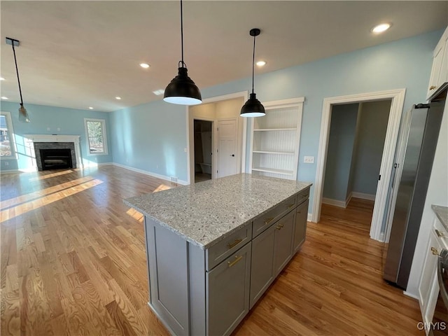 kitchen featuring light wood finished floors, a fireplace, gray cabinets, and freestanding refrigerator