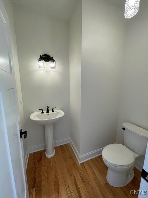 half bathroom featuring toilet, baseboards, and wood finished floors