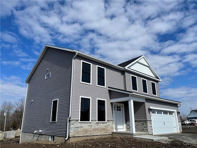 view of front of property featuring stone siding, a garage, and driveway