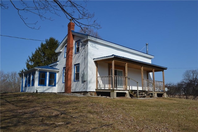 view of front facade featuring covered porch, a chimney, and a front yard