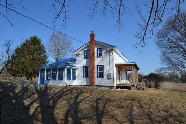 exterior space featuring a yard, a porch, and a chimney