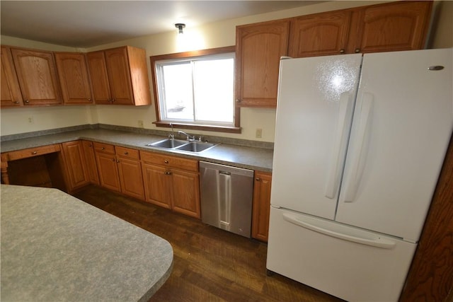 kitchen with a sink, brown cabinets, freestanding refrigerator, and stainless steel dishwasher