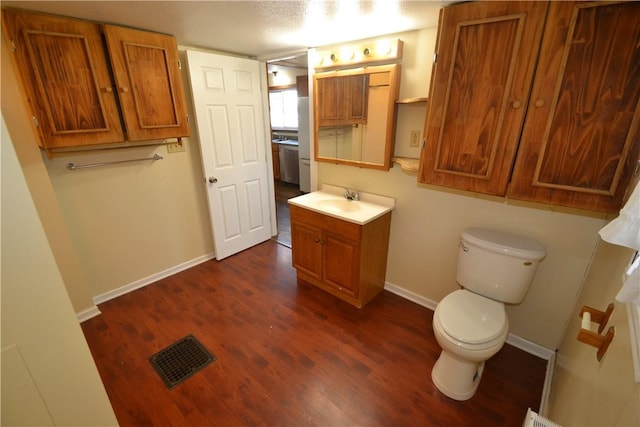 bathroom featuring visible vents, baseboards, toilet, wood finished floors, and vanity