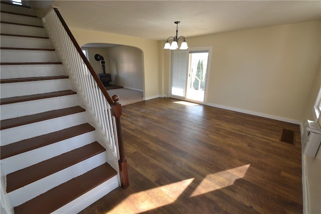 interior space featuring visible vents, wood finished floors, arched walkways, baseboards, and a chandelier