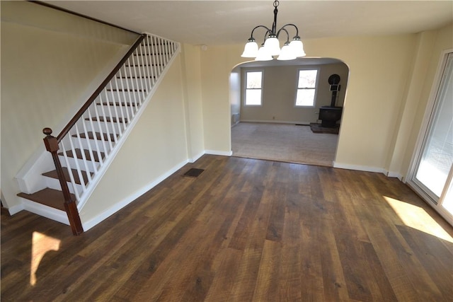 unfurnished dining area with visible vents, baseboards, stairs, dark wood-style floors, and arched walkways