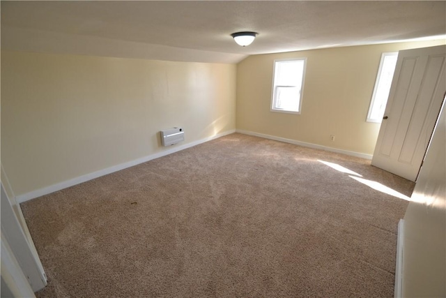 unfurnished bedroom featuring heating unit, baseboards, carpet flooring, and vaulted ceiling