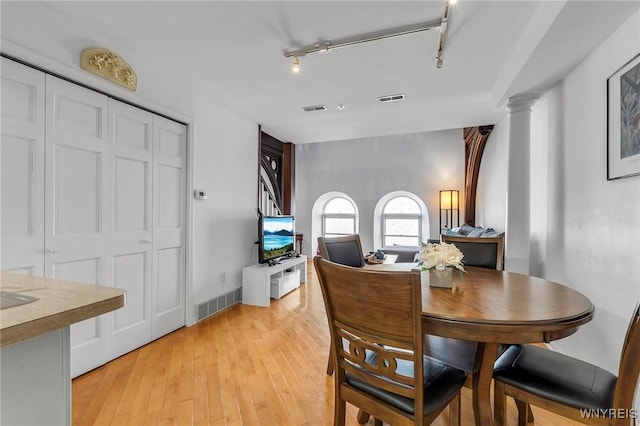 dining space with visible vents, light wood-type flooring, and decorative columns