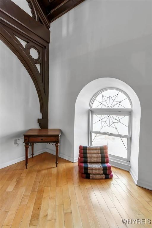 living area featuring arched walkways, light wood-type flooring, and baseboards