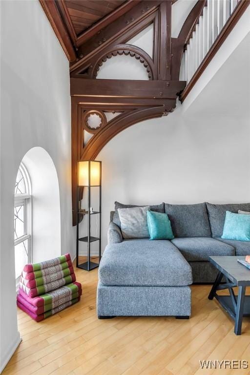 living room with wood finished floors, arched walkways, and a towering ceiling