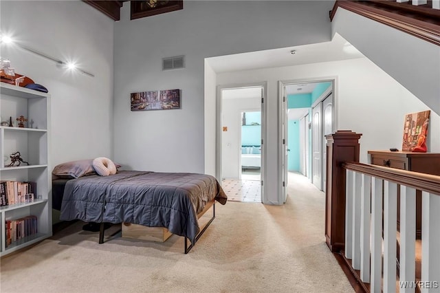 bedroom with visible vents, light colored carpet, and a towering ceiling