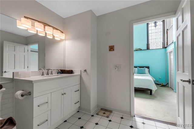 ensuite bathroom featuring tile patterned floors, vanity, ensuite bathroom, and baseboards