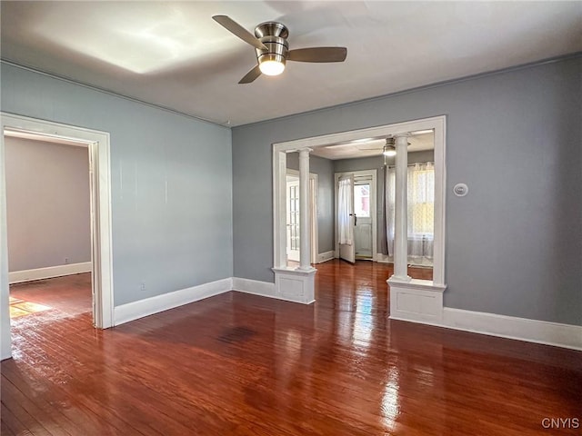 empty room featuring ceiling fan, decorative columns, baseboards, and hardwood / wood-style floors