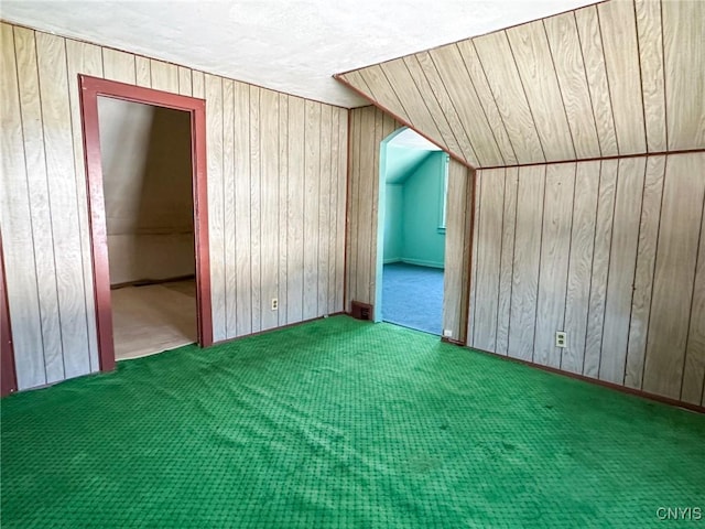 bonus room with wood walls and carpet floors