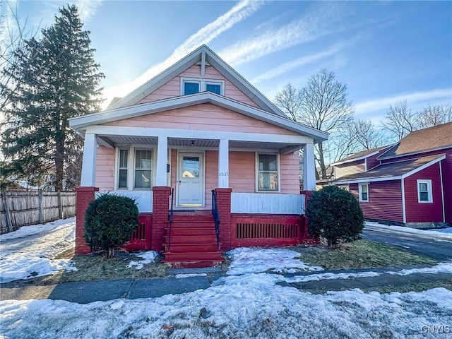 view of front of home featuring brick siding, a porch, and fence