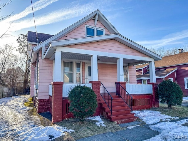 bungalow with roof with shingles, covered porch, and fence